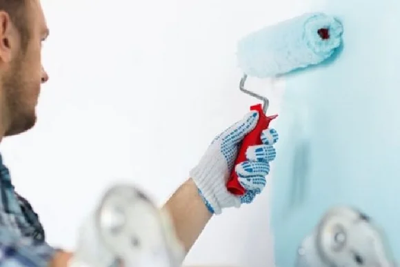 Person streicht Wand mit Farbrolle